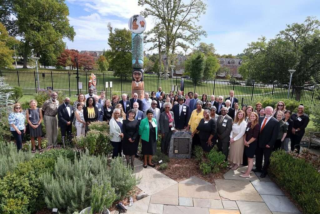 Members of the Voices For Our Fathers Legacy Foundation, who are descendants of men unethically treated in the Untreated Syphilis Study, and NIH leaders gather around the commemorative plaque in the National Library of Medicine herb garden.